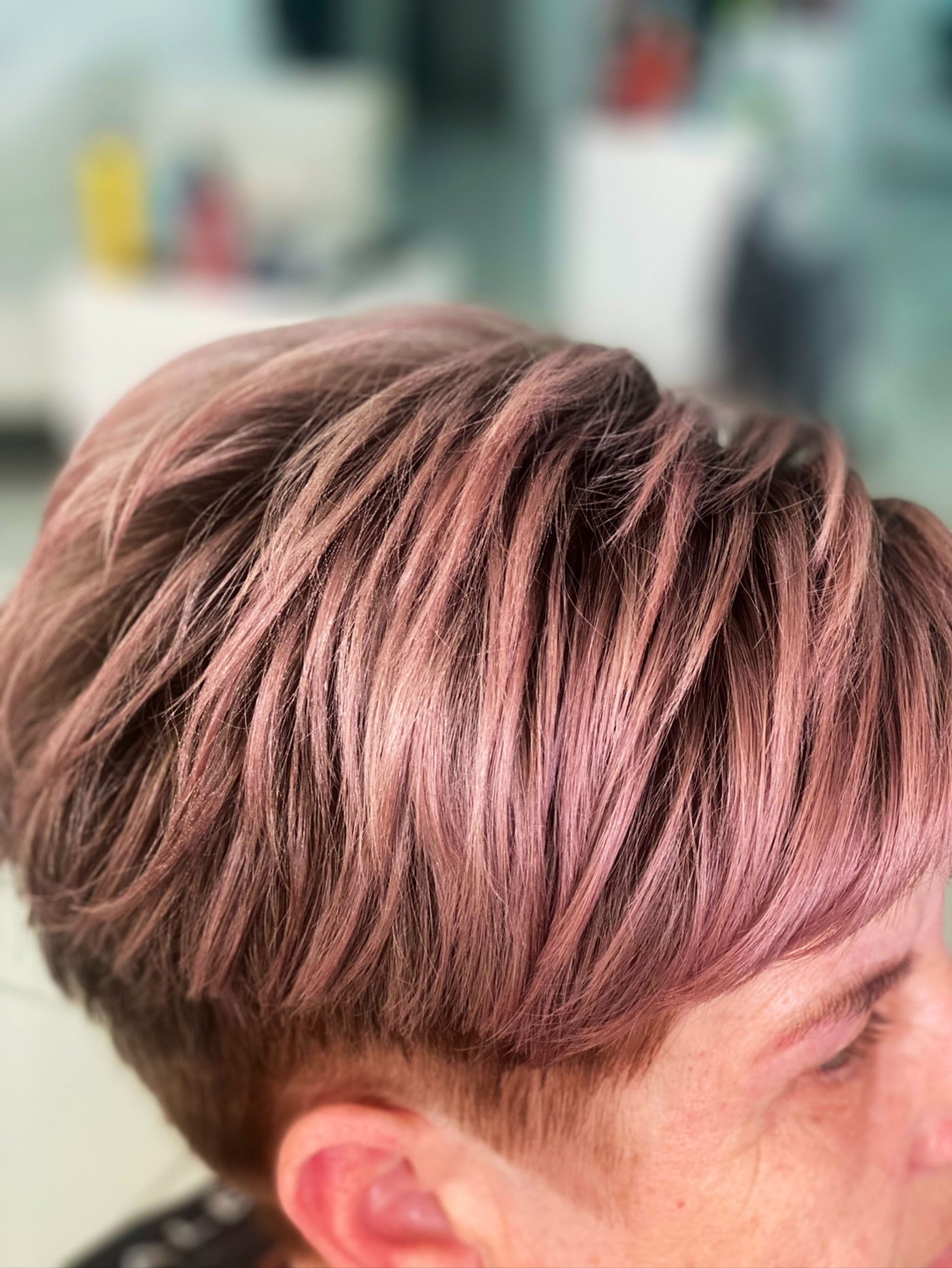 Korte damescoupe met een roze tint, van opzij gezien