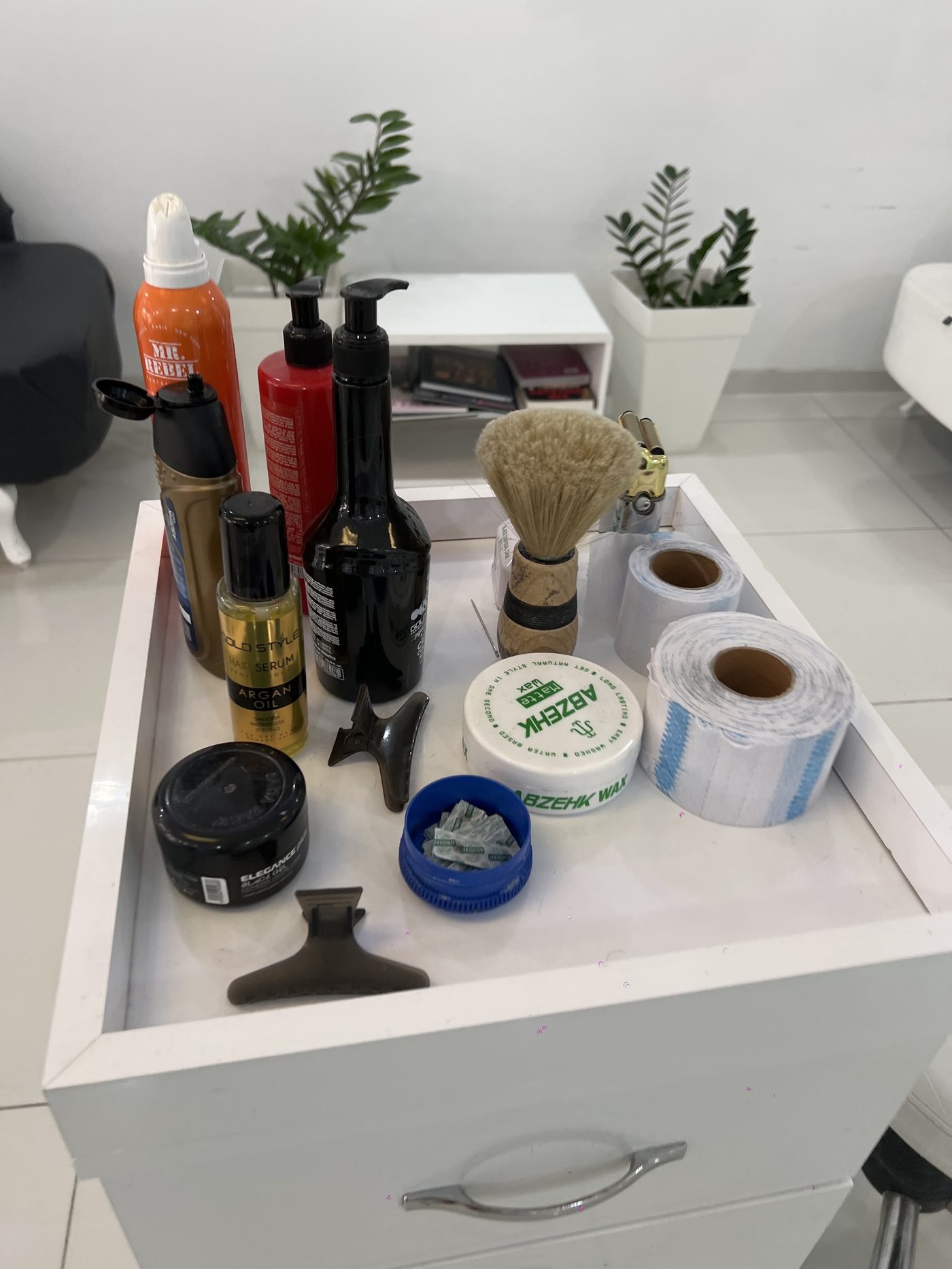 Wit werkkarretje met haarproducten, een scheerkwast en nekpapier